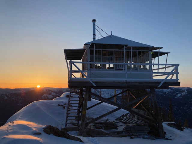 a lifeguard tower on top of a mountain at sunset