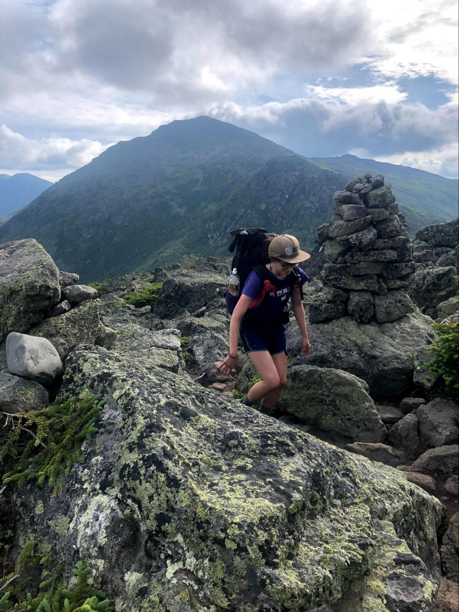 a woman hiking up a mountain with a backpack