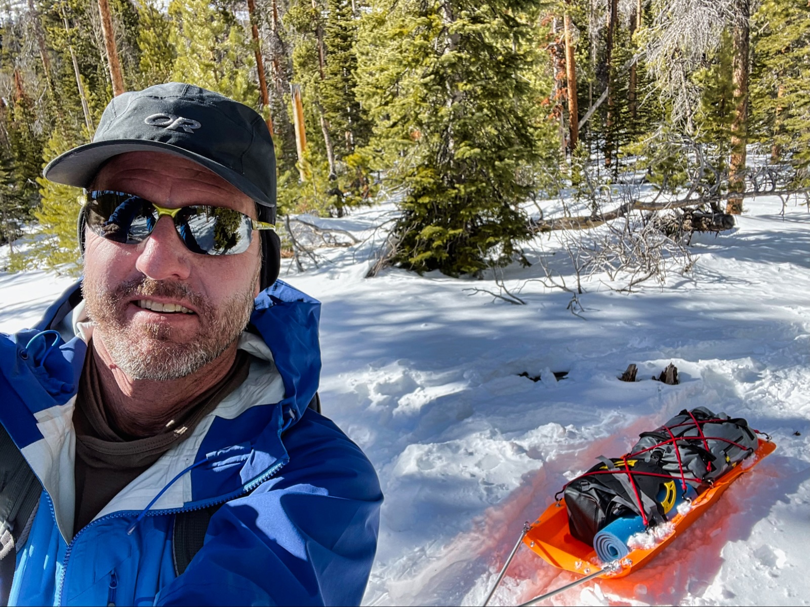a man standing in the snow next to a sled