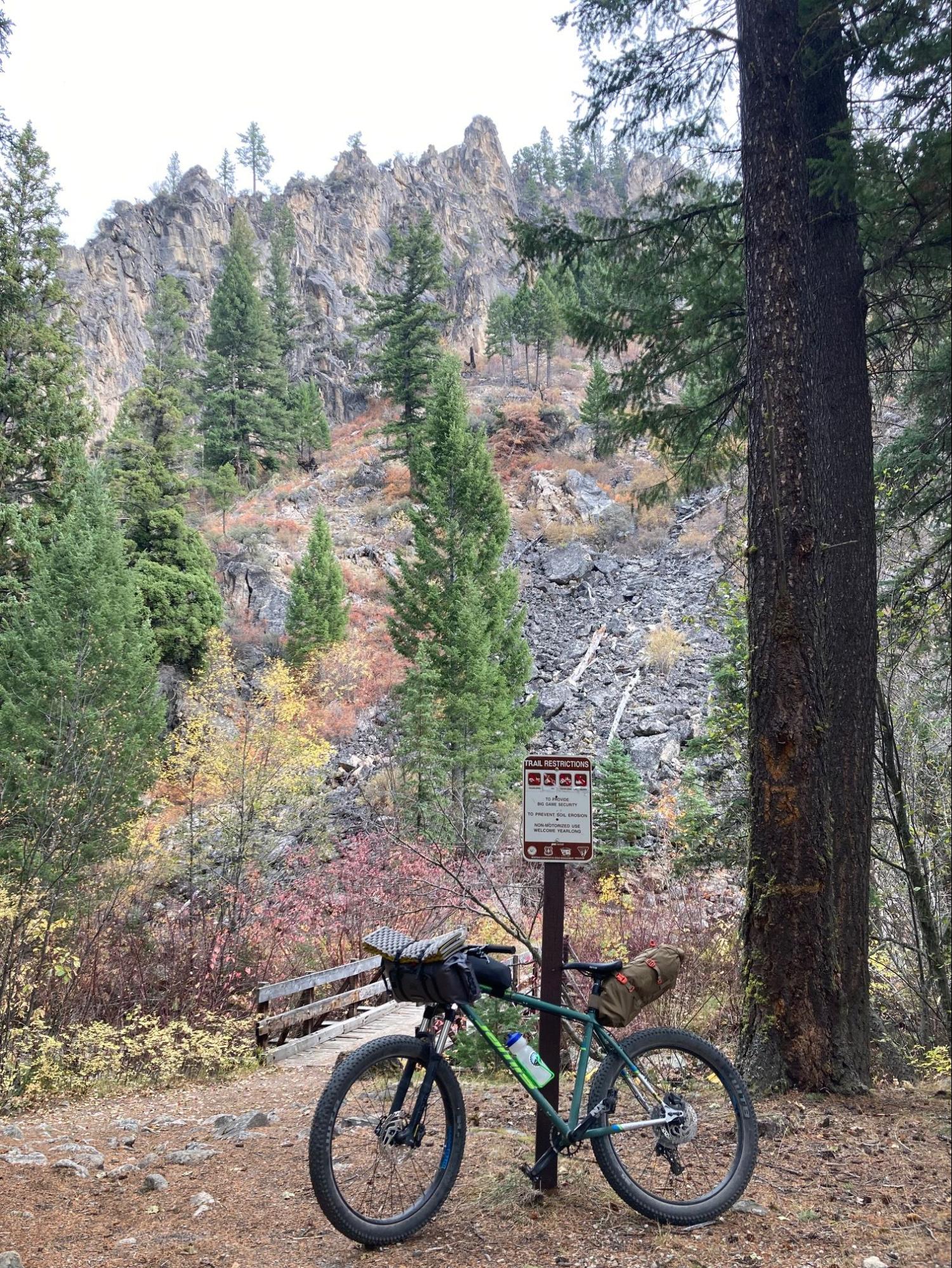 a bike parked next to a sign in the woods