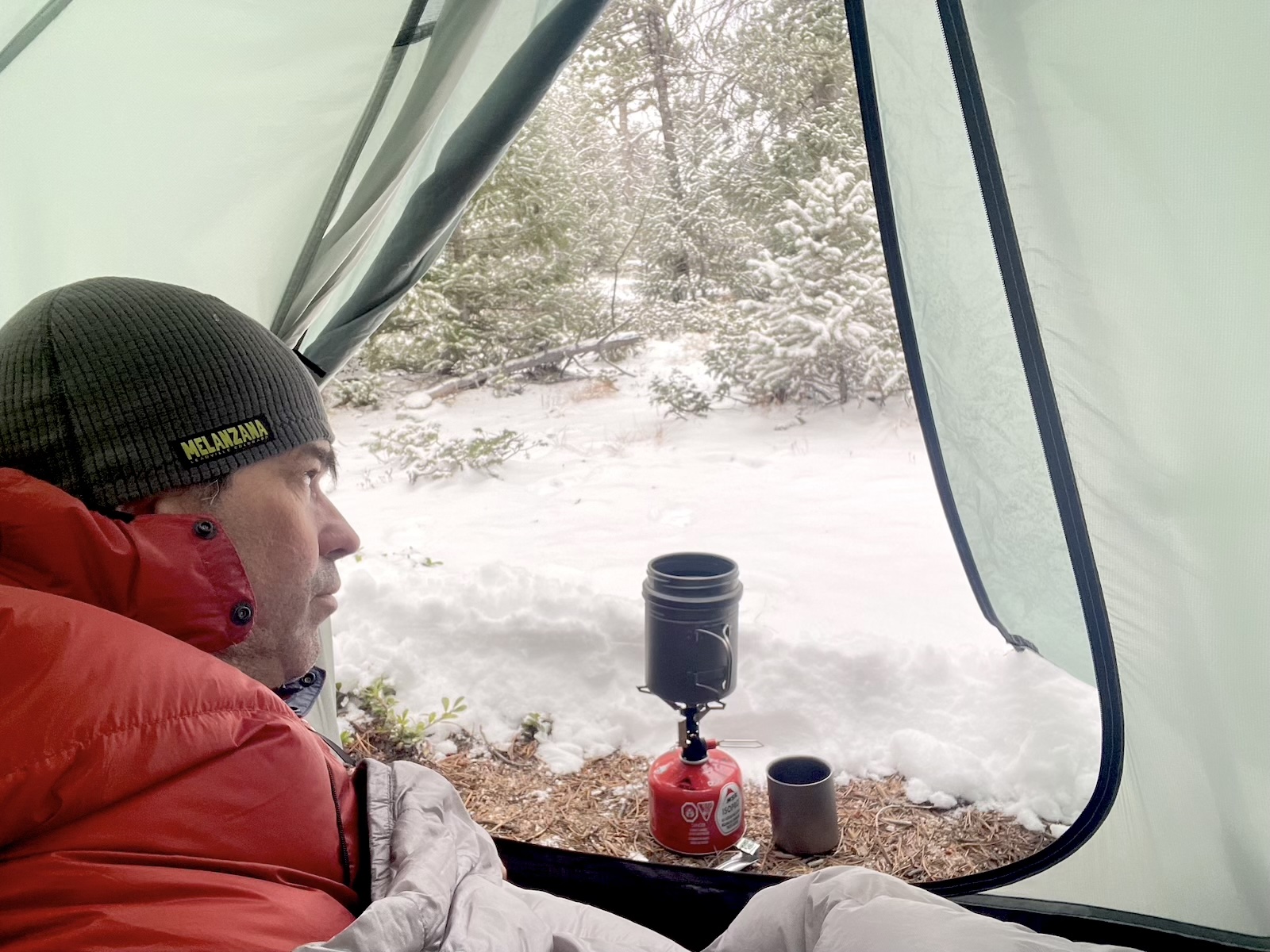 a man sitting inside of a tent in the snow