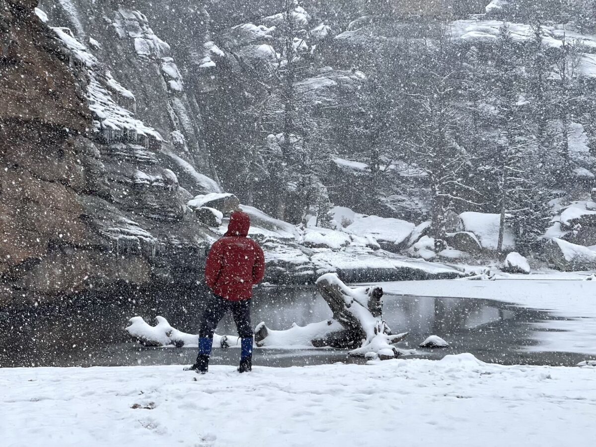 a person standing in the snow near a river