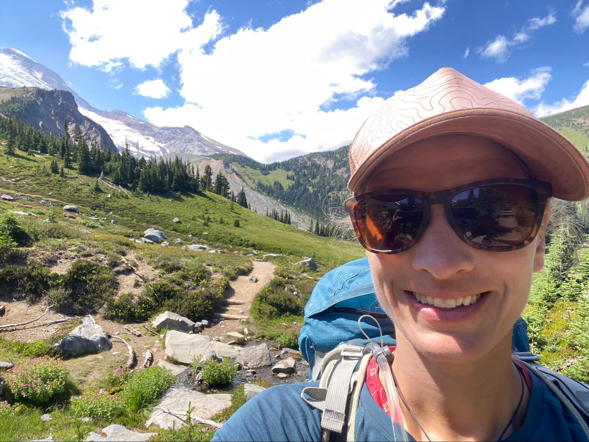 a woman wearing a hat and sunglasses on a hike