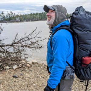 a man with a backpack is standing by the water