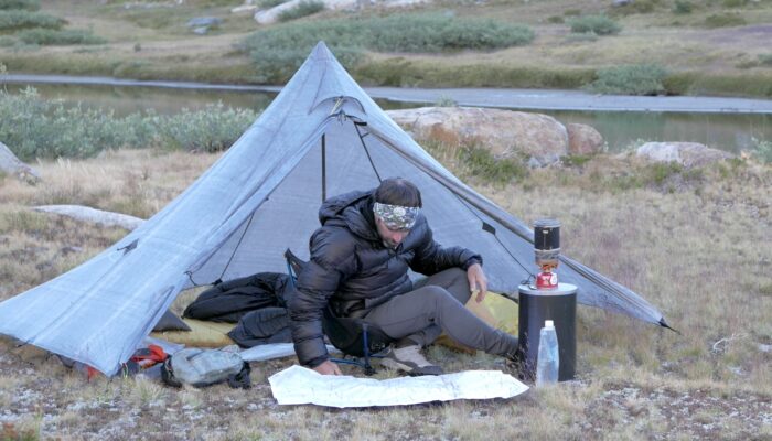 man at campsite with bear canister