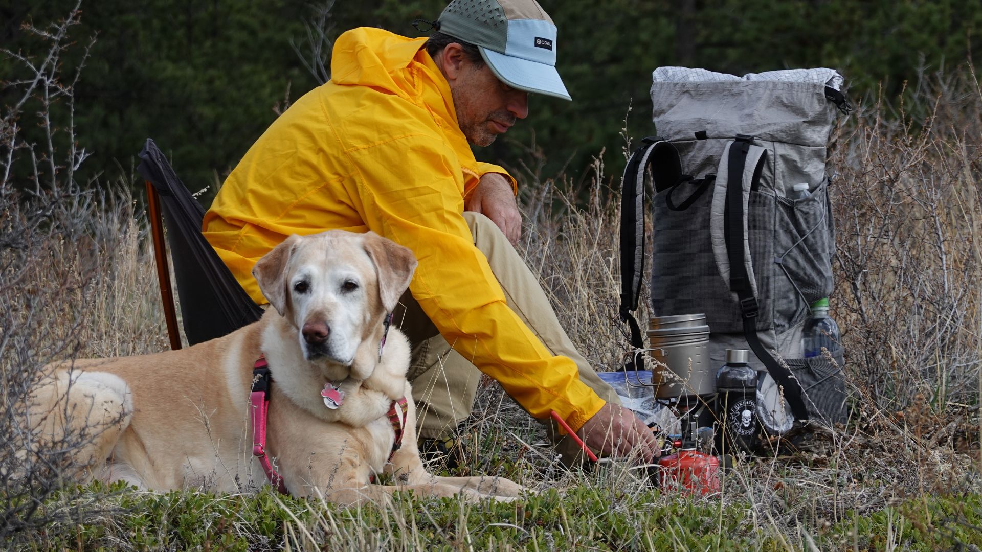 a man in a yellow rain coat sitting next to a dog