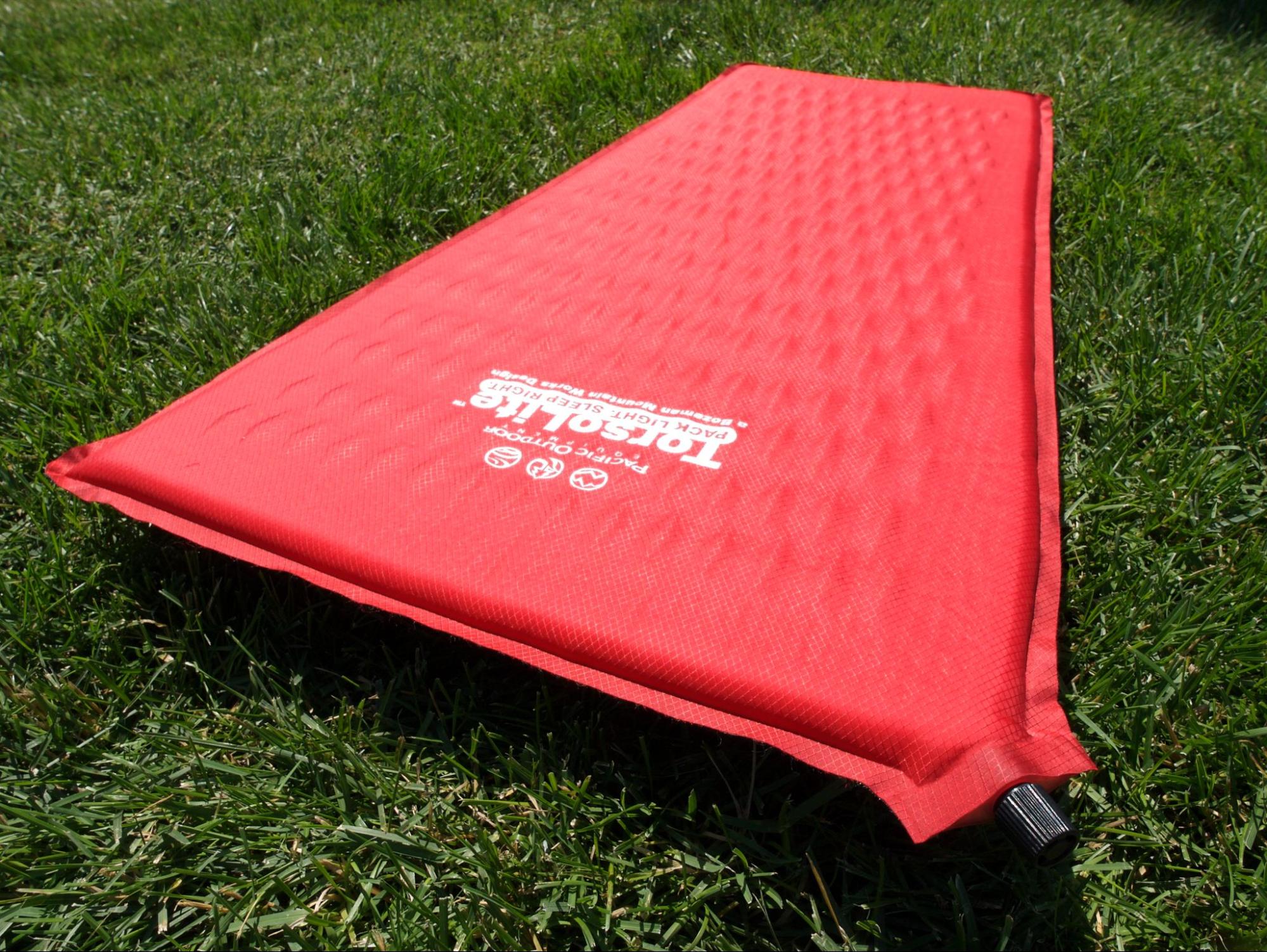a red mat laying on top of a lush green field