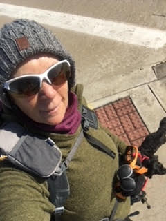 a woman wearing a hat and sunglasses standing next to a fire hydrant