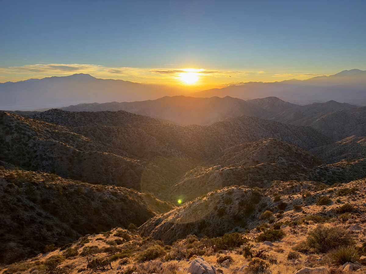 the sun is setting over the mountains in the desert