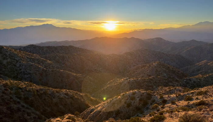 the sun is setting over the mountains in the desert