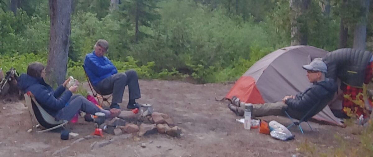 three backpackers around a campfire