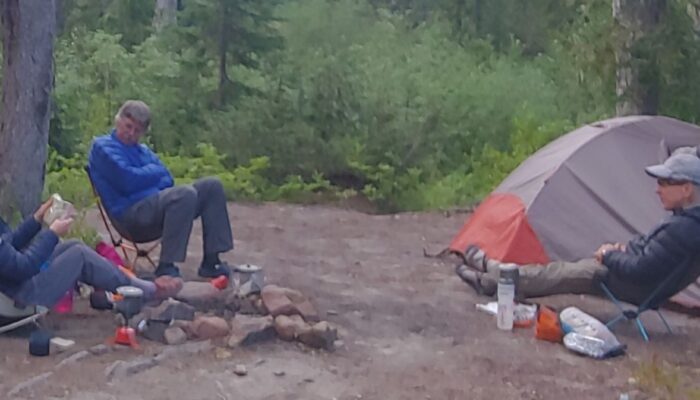 three backpackers around a campfire