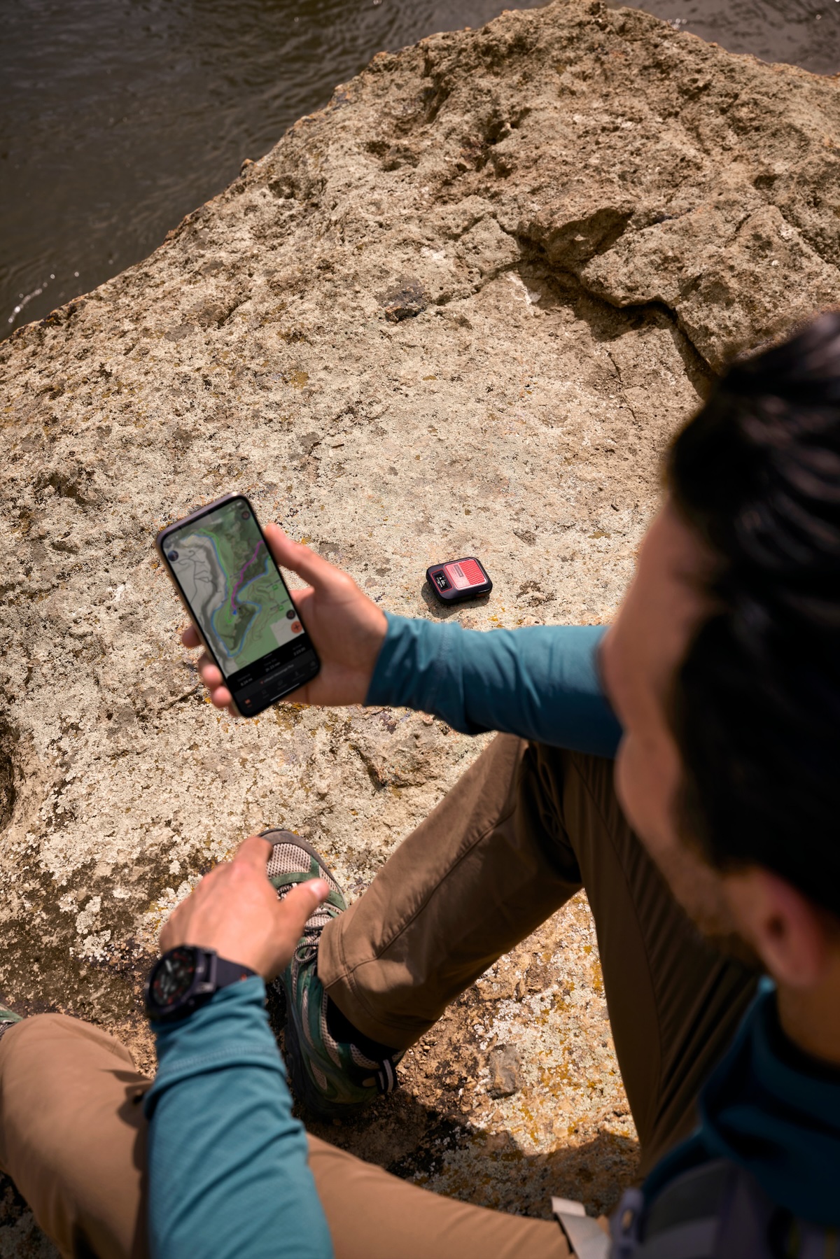 man using a smartphone for navigation while connected to a satellite messaging device