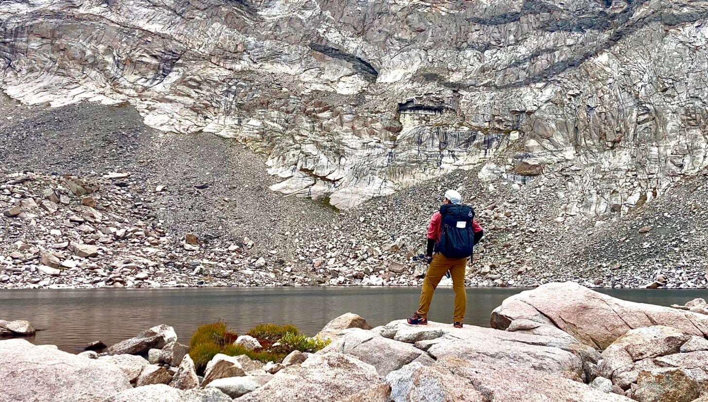 hiker standing near an alpine lake