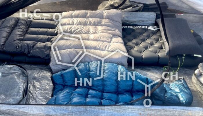 a tent with a sleep system inside - quilt, pad, pillow, down sweater; overlaid with the melatonin molecule