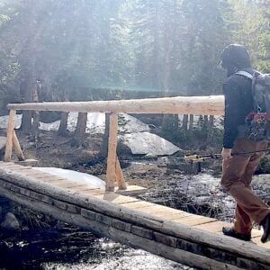 man wearing backpacking over bridge