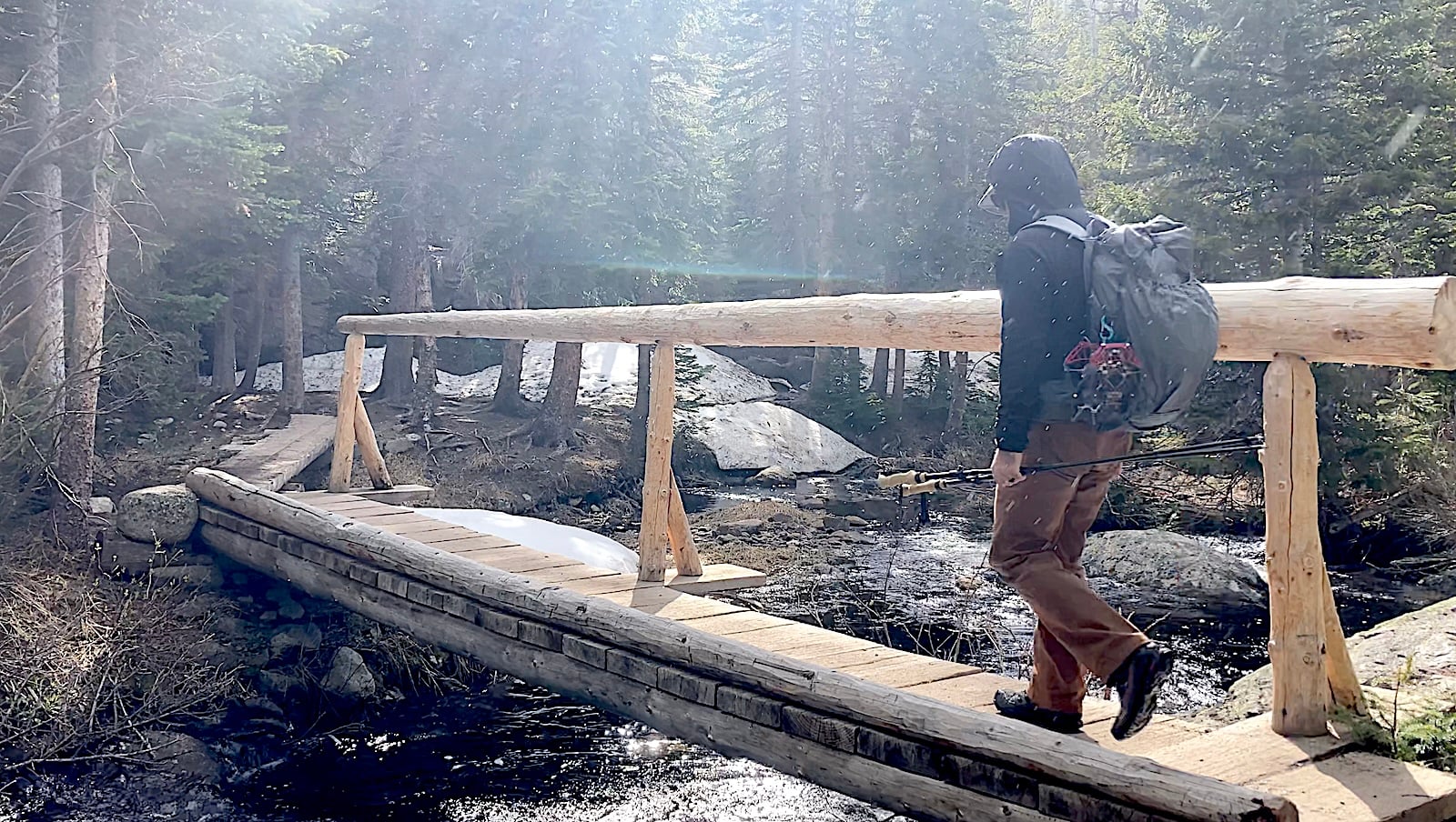 man wearing backpacking over bridge