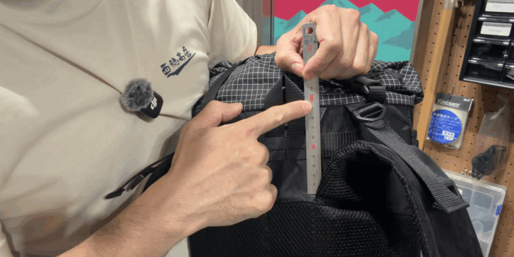 Measurement of backpack height above the shoulder-strap attachment using a ruler on a prototype pack.