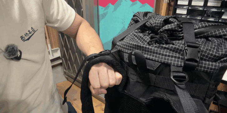 Close-up of a wearer tightening a backpack load lifter after adjusting the shoulder straps.