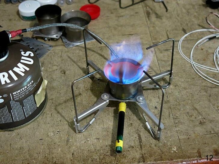 Remote canister stove operating with a glowing burner head.