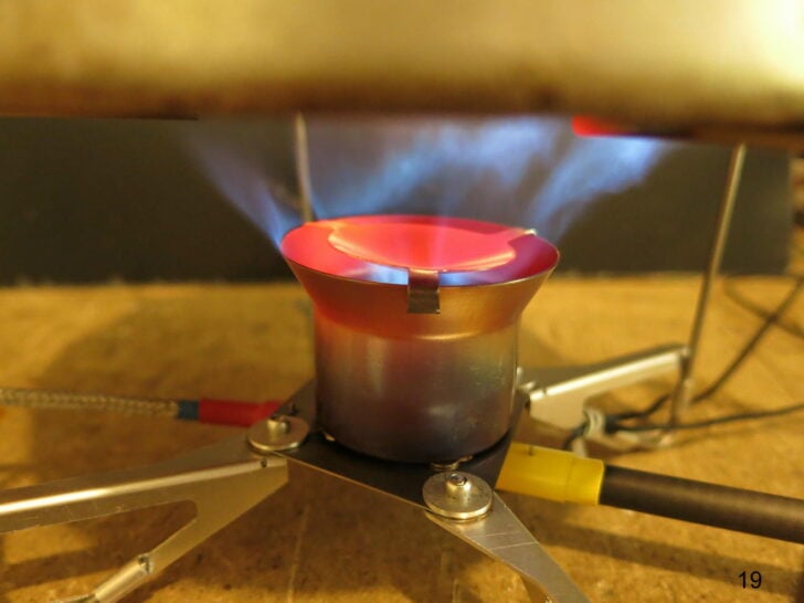 Close-up of a glowing stove burner operating beneath a pot.