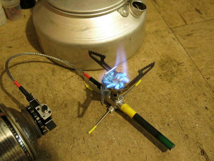 Compact remote canister stove burning beneath a kettle.